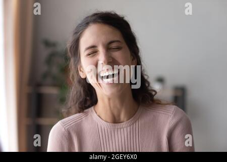 Bonne jeune femme riant seule à la maison Banque D'Images