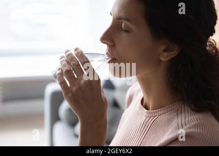 Femme tenant de l'eau potable en verre, vue de face de côté de gros plan Banque D'Images