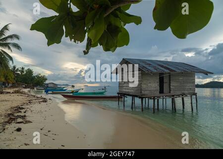 Yenbeser, Indonésie - 14 octobre 2019 : quelques bateaux amarrés le long de la rive d'une plage et d'une petite maison au-dessus de l'eau, Raja Ampat Banque D'Images