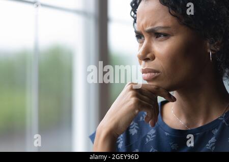 Frustrée et préoccupée femme afro-américaine du millénaire regardant par la fenêtre Banque D'Images