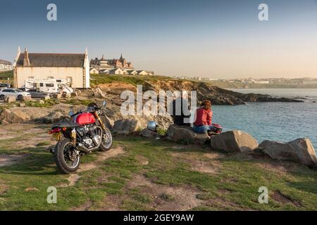 Un motocycliste et son passager assis sur des rochers surplombant Little Fistral à Newquay, en Cornouailles. Banque D'Images