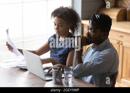 Un couple marié afro-américain sérieux examine les factures mensuelles Banque D'Images