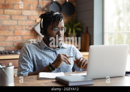 Un étudiant afro-américain sérieux dans les écouteurs regardant le séminaire en ligne Banque D'Images