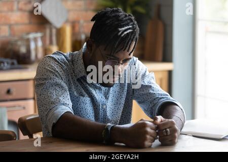 Triste homme noir attentionné assis à table, s'ennuyant, Banque D'Images