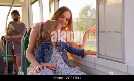 Promenades en famille dans les transports en commun, mère avec petite fille s'asseoir ensemble et regarder le tram de fenêtre Banque D'Images