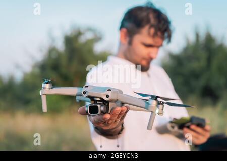Homme tenant un drone amateur compact avant le vol. Pilotage du quadricoptère à l'extérieur. Prise de vue aérienne. Filmer la nature depuis le haut Banque D'Images