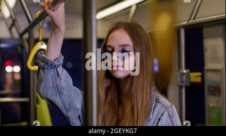 Une jeune femme fatiguée et ennuyeuse se tenant seule dans le transport en bus après une dure journée de travail et s'endormant Banque D'Images