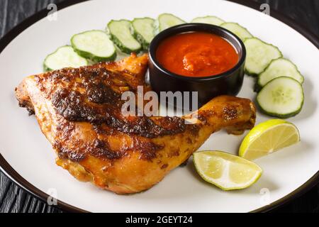 Ayam bakar est un plat indonésien et malaisien, composé de poulet grillé au charbon de bois servi avec concombre et sauce chaude dans l'assiette sur le Banque D'Images
