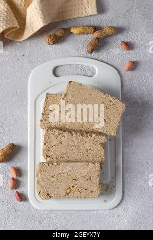 Halva de tournesol douce avec arachide sur tableau blanc sur fond gris clair. Banque D'Images