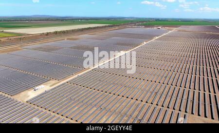 vue aérienne par drone d'une vaste ferme d'énergie solaire avec des champs agricoles en arrière-plan rural. Banque D'Images