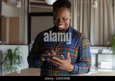 Sourire Afro-américain homme utiliser la tablette communiquer en ligne Banque D'Images