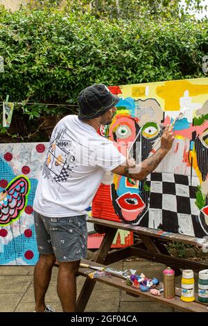 Jeune artiste masculin finissant sa peinture sur toile debout dans un jardin. Banque D'Images