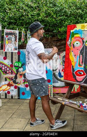 Jeune artiste masculin finissant sa peinture sur toile debout dans un jardin. Banque D'Images