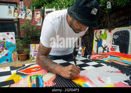 Jeune artiste masculin finissant sa peinture sur toile debout dans un jardin. Banque D'Images