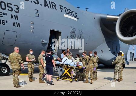 Ramstein Air base, Allemagne. 22 août 2021. Le personnel de soutien médical du 86e groupe médical aide une mère et une famille afghanes à quitter un C-17 de l'US Air Force, panneau d'appel REACH 828, quelques instants après qu'elle a livré un enfant à bord de l'avion à l'atterrissage à la base aérienne de Ramstein, en Allemagne, le 21 août 2021. Au cours d'un vol d'évacuation à partir d'une base de stadification intermédiaire au Moyen-Orient, la mère est entrée au travail et a commencé à éprouver des complications dues à l'hypertension artérielle. Crédit : UPI/Alay Live News Banque D'Images