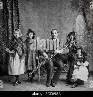 Un portrait du début du XXe siècle d'une famille musicale dans le comté de Cork, en Irlande. Les filles de gauche sont prêtes à danser une autre joue un coup de sifflet de penny. La jeune fille à droite joue des tuyaux Uilleann simplifiés tandis que le père joue un ensemble complet. Banque D'Images