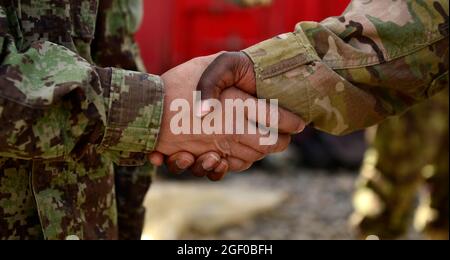 U.S. Air Force Tech. Sgt. Earnest Buffin, 4e Division d'infanterie, conseiller principal en logistique pour le département de logistique de l'Armée nationale de l'Afghanistan (ANA) dans la région sud, accueille un soldat de l'ANA à son arrivée à la base opérationnelle Forward, Lindsey, province de Kandahar, Afghanistan, le 13 mars, 2014. Buffin a mené 12 aviateurs sur le site lors d'une mission avec le colonel Timothy Lee de la Force aérienne des États-Unis, 466e commandant du Groupe expéditionnaire de l'Air. Buffin, originaire de Dallas, au Texas, est déployé à partir du 22e Escadron de préparation logistique de la base aérienne de McConnell, Kan., et est responsable des documents d'entretien des véhicules, ANA Weapon Banque D'Images