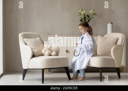 Mignon enfant jouant docteur à la maison, portant un manteau blanc surdimensionné Banque D'Images