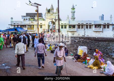 Mumbai, Maharashtra, Inde : les pèlerins marchent au-delà des mendiants sur la chaussée menant au 19ème siècle Haji Ali Dargah et la mosquée qui contient le tombeau Banque D'Images