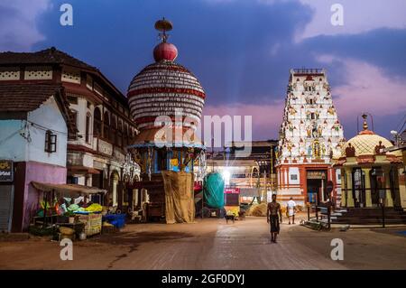 Udupi, Karnataka, Inde : UN pèlerin marche avant l'aube depuis le temple Krishna du XIIIe siècle et de grands chars processionnels à l'extérieur. Le temple a été trouvé Banque D'Images