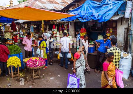 Mysore, Karnataka, Inde : les femmes marchent devant les étals de fleurs au marché de Devaraja. Banque D'Images