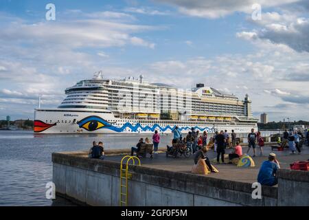 Sommerabendmunstimg an der Kiellinie. Die AIDA cara läuft aus. Im Vordergrund beobachten tanzende Menschen das Geschehen Banque D'Images