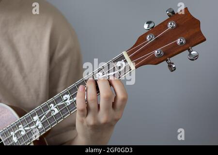 Femme jouant à la main ukulele sur fond blanc Banque D'Images