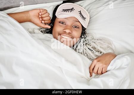 Portrait d'une jeune femme afro-américaine se réveillant le matin et souriant à l'appareil photo Banque D'Images