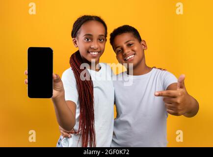 Adorable adolescent noir frère et soeur montrant smartphone, maquette Banque D'Images