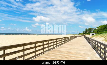 Longue promenade en bois le long de la plage de sable de la mer Baltique dans le village de Yantarny, région de Kaliningrad, Russie. Banque D'Images