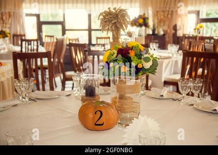 Décoration festive de style automnal avec numérotation des tables sur citrouilles dans la salle de banquet. Floristerie et décoration d'événements arrangements floraux. Banque D'Images