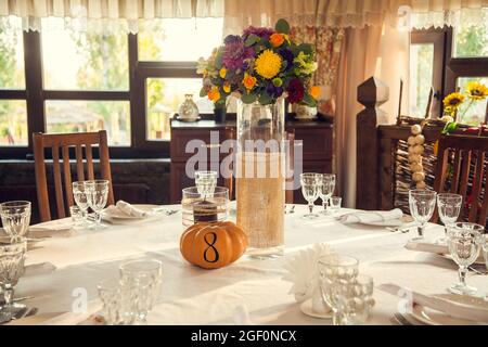 Décoration festive de style automnal avec numérotation des tables sur citrouilles dans la salle de banquet. Floristerie et décoration d'événements arrangements floraux. Banque D'Images