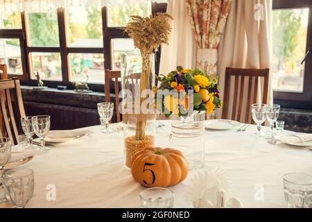 Décoration festive de style automnal avec numérotation des tables sur citrouilles dans la salle de banquet. Floristerie et décoration d'événements arrangements floraux. Banque D'Images