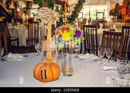 Décoration festive de style automnal avec numérotation des tables sur citrouilles dans la salle de banquet. Floristerie et décoration d'événements arrangements floraux. Banque D'Images