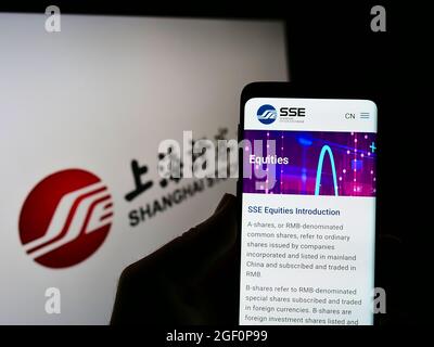 Personne tenant un téléphone portable avec la page web de la Bourse chinoise de Shanghai (SSE) à l'écran devant le logo. Concentrez-vous sur le centre de l'écran du téléphone. Banque D'Images