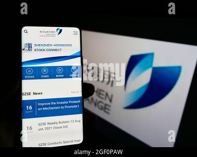 Personne tenant le téléphone portable avec la page web de la Bourse chinoise de Shenzhen (SZSE) à l'écran devant le logo. Concentrez-vous sur le centre de l'écran du téléphone. Banque D'Images