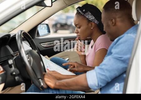 Couple afro-américain voyageant en voiture, s'est perdu, en vérifiant la carte Banque D'Images