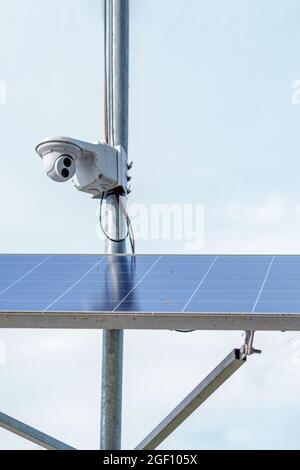 Caméra de surveillance à énergie solaire. Panneaux solaires alimentant une caméra de surveillance dans un parc urbain sur fond de ciel bleu. Sécurité et nettoyage Banque D'Images