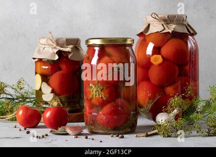 Différentes tomates marinées en pots pour l'hiver sur fond gris clair Banque D'Images