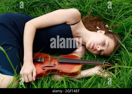 Belle fille à poil brun d'apparence asiatique avec un violon dans la nature. Musicien dans la nature. Musique classique Banque D'Images