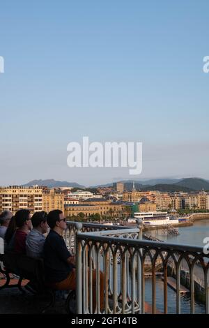 Personnes assises sur un banc d'observation de la baie de la Contxa à San Sebastian, Espagne Banque D'Images