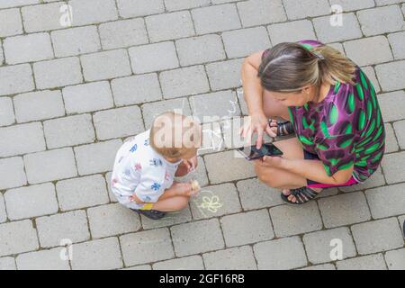 vue en descente sur un enfant qui dessine sur des dalles et une femme qui l'observe. Suède. Banque D'Images