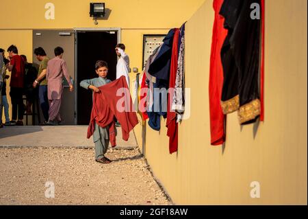 Base aérienne d'Al Udeied, Qatar. 21 août 2021. Un garçon afghan met la lessive à sécher dans une installation de logement temporaire pour les réfugiés évacués de Kaboul le 21 août 2021 à la base aérienne d'Al Udeied, au Qatar. Credit: Planetpix/Alamy Live News Banque D'Images