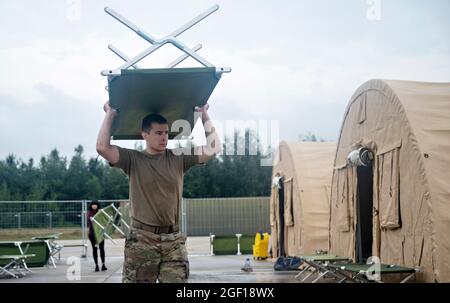 Ramstein Miesenbach, Allemagne. 22 août 2021. U.S. Air Force SSTGT. Jared Caton, 86e Escadron de maintenance du matériel, transporte un berceau dans un logement pour les réfugiés afghans à la base aérienne de Ramstein le 22 août 2021 à Ramstein-Miesenbach, en Allemagne. La base aérienne de Ramstein fournit un hébergement temporaire aux personnes évacuées d'Afghanistan dans le cadre de l'opération alliés refuge. Credit: Planetpix/Alamy Live News Banque D'Images