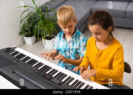 Leçon de musique pour les enfants sur le piano. L'idée d'activités pour l'enfant à la maison pendant la quarantaine. Concept de musique Banque D'Images