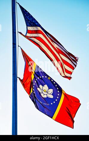 Un drapeau américain et le nouveau drapeau du Mississippi volent ensemble sur un poteau de drapeau devant une école, le 21 août 2021, à Kiln, Mississippi. Banque D'Images