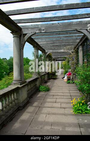 Les femmes âgées s'assoient sur un banc sous la pergola en bois à Hill Garden et Pergola, Hampstead Heath, Londres, Royaume-Uni Banque D'Images