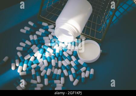 Pilules dans un panier d'épicerie. Capsules de médicaments sur la table. Acheteur à la pharmacie. Commande de médicaments en ligne. Pilules sur fond bleu dans une boîte. Banque D'Images