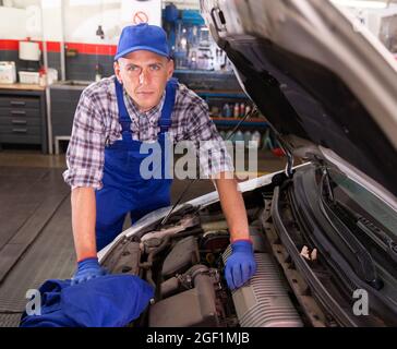 Homme positif mécanician de voiture de réparation de voiture dans le service de réparation d'auto Banque D'Images