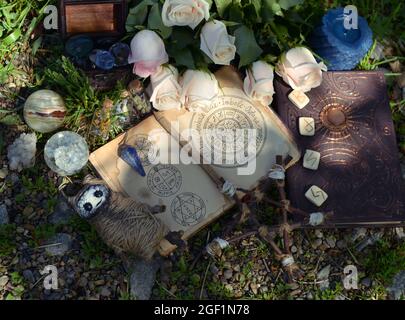 Rituel Wicca avec journal de sorcière ouvert, pentagramme et poupée voodoo sur l'herbe. Arrière-plan ésotérique, gothique et occulte, concept mystique et wicca d'Halloween Banque D'Images